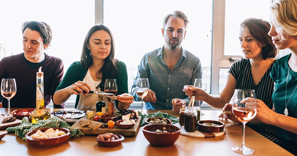 Group of friends at a dinner table with wine and Spanish tapas.